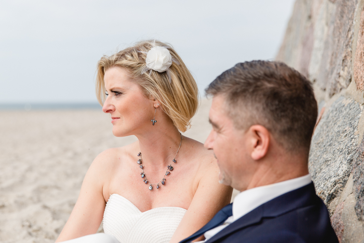 Brautpaar sitzt am Strand von Warnemünde.