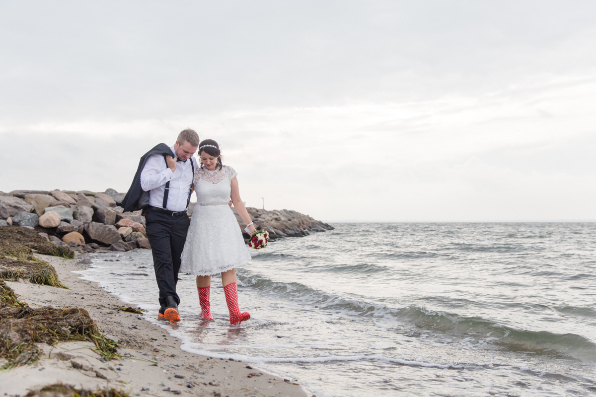 Verliebtes Paar mit Gummistiefeln am Meer