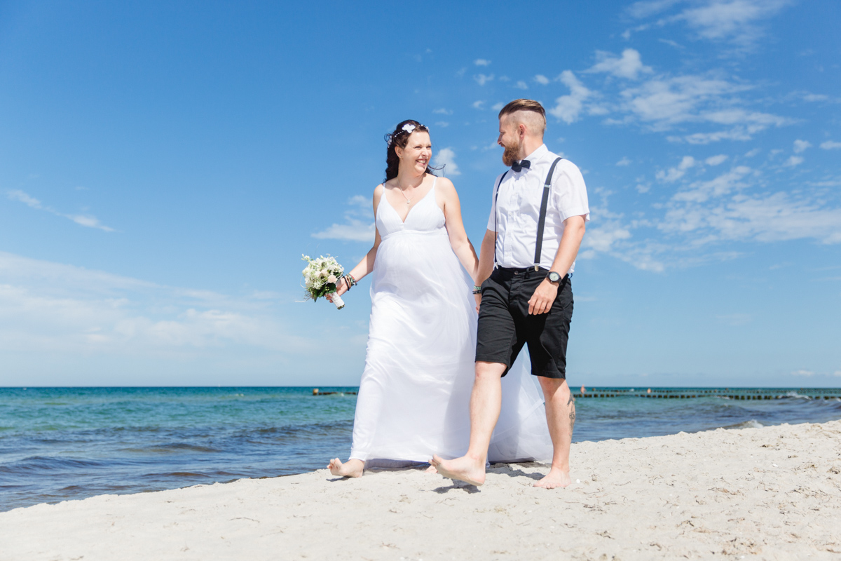 Schwangere Braut und Bräutigam am Strand.