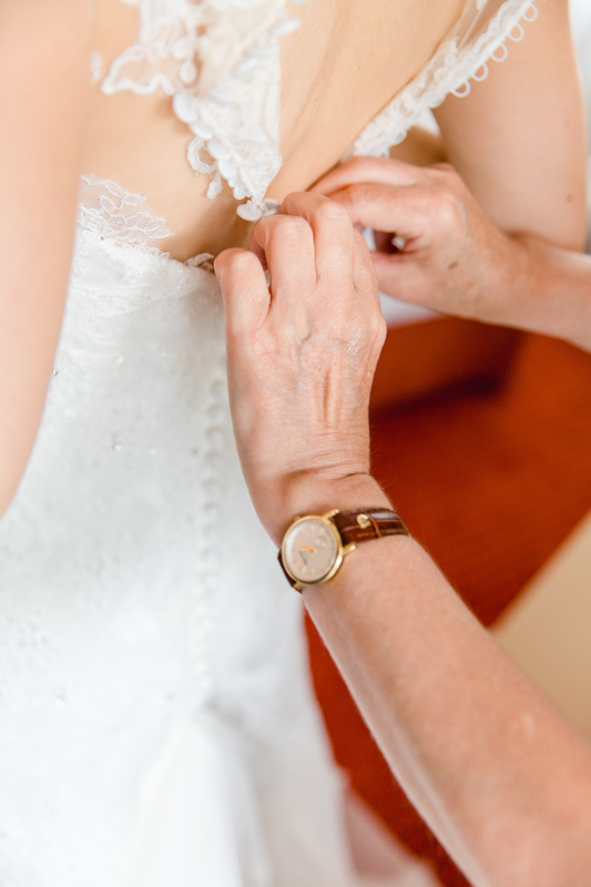 Hochzeitsfoto Brautkleid wird geschlossen.