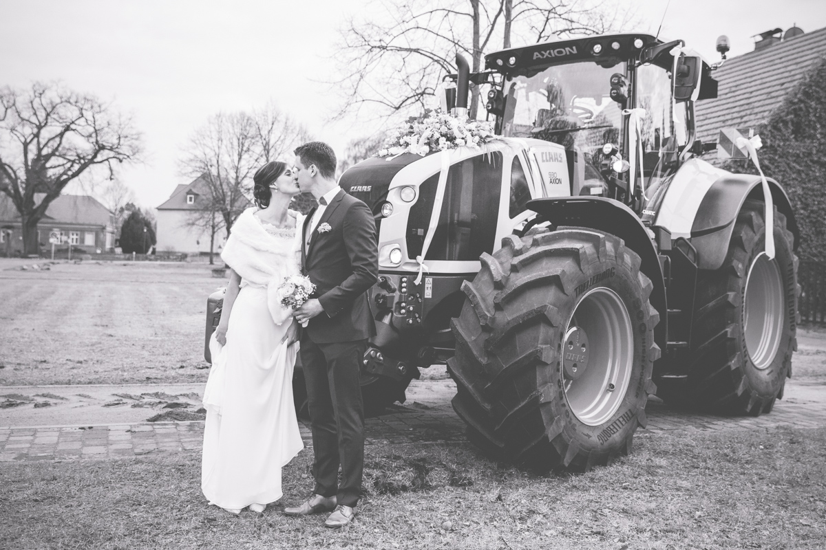 Brautpaar vor ihrem Hochzeitsauto, dem Traktor.