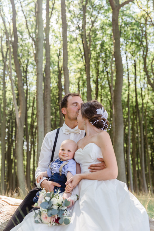 Hochzeitsfotos mit Kind, aufgenommen im Wald.