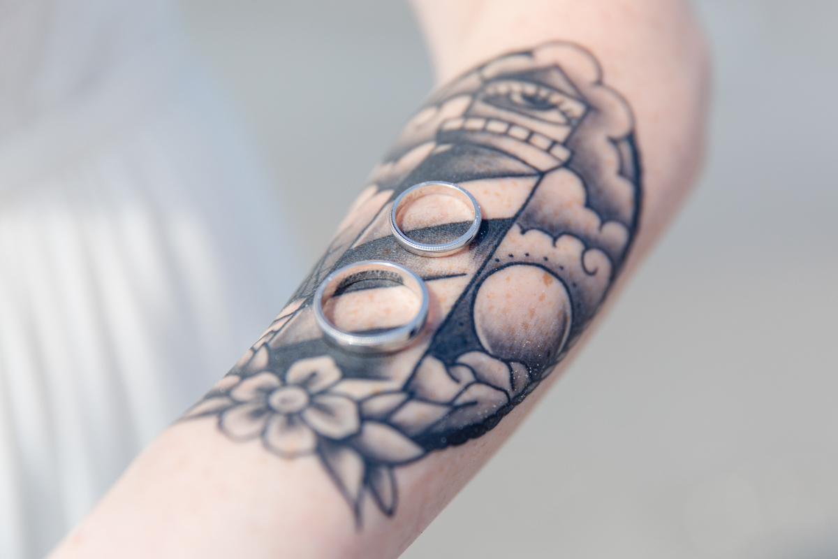 Eheringe fotografiert auf dem tätowierten Arm.