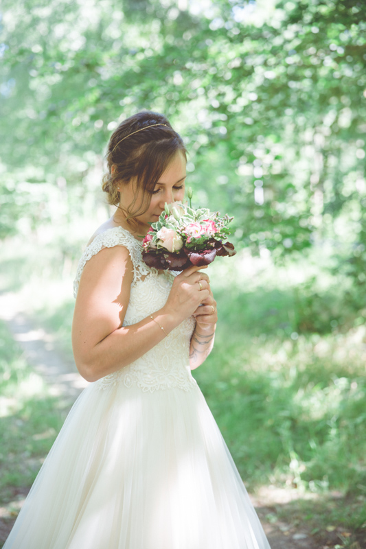 Braut mit Brautstrauß im Wald fotografiert.