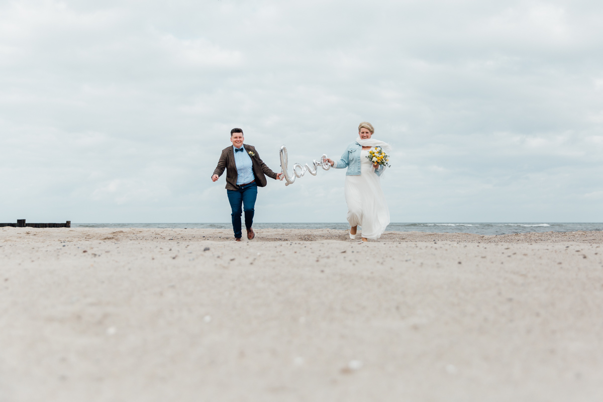 Brautppar mit Luftballon am Strand.