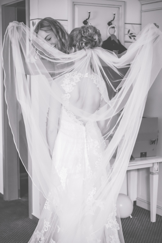 Braut beim Anziehen ihres Kleides vor der Trauung.