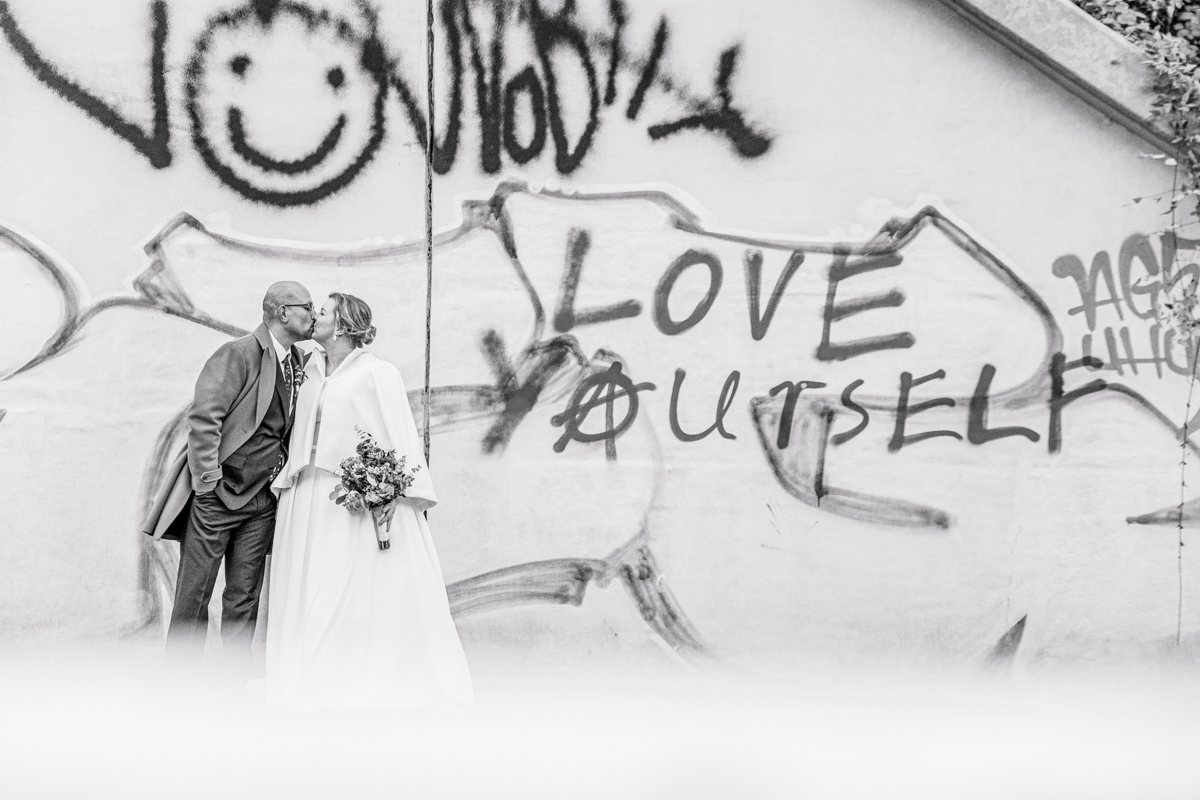 Brautpaar vor Grafitiwand.