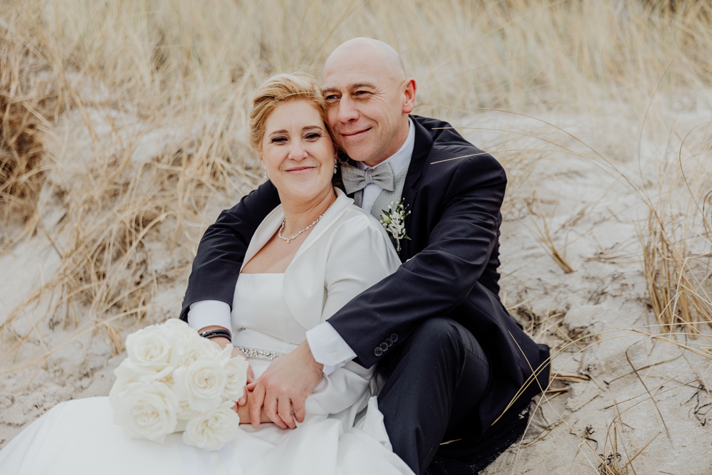 Brautpaar sitzt in den Dünen